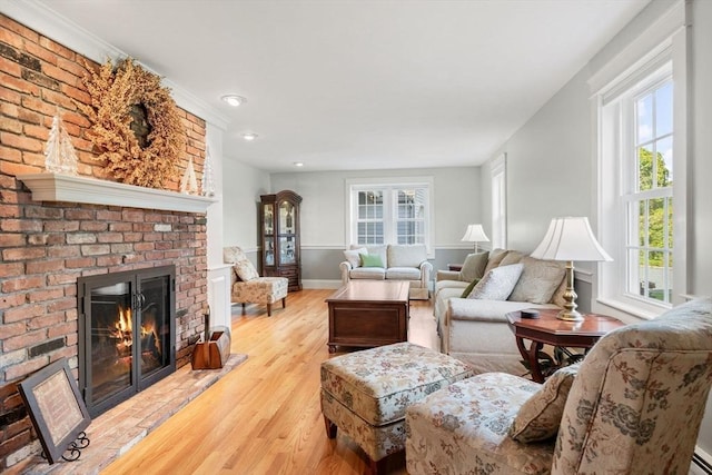 living room with baseboards, a brick fireplace, and wood finished floors