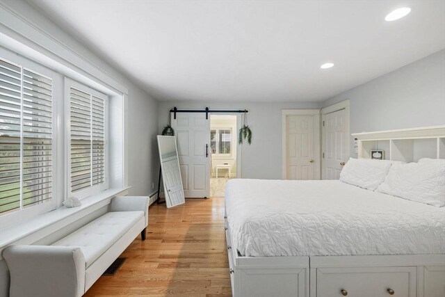 bedroom with recessed lighting, a barn door, light wood-style flooring, and ensuite bathroom