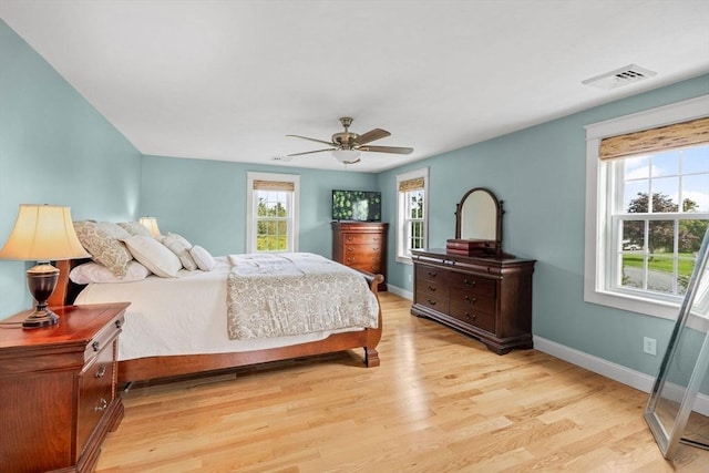 bedroom featuring a ceiling fan, light wood-style floors, visible vents, and baseboards