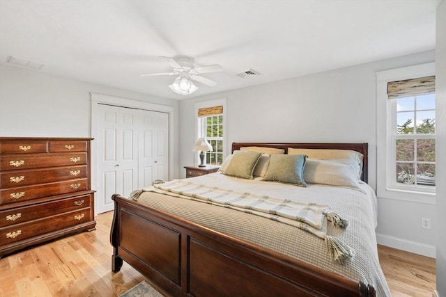 bedroom with light wood-type flooring, visible vents, a ceiling fan, a closet, and baseboards