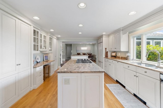 kitchen with stainless steel gas cooktop, white cabinetry, a center island, and a sink