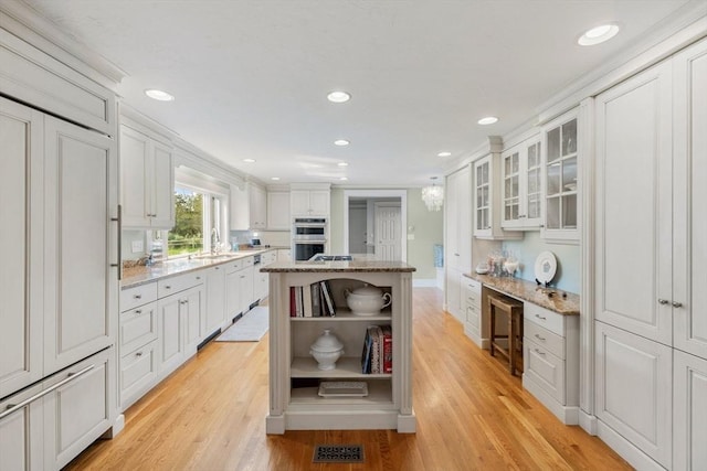 kitchen with visible vents, a sink, light wood-type flooring, white cabinets, and open shelves