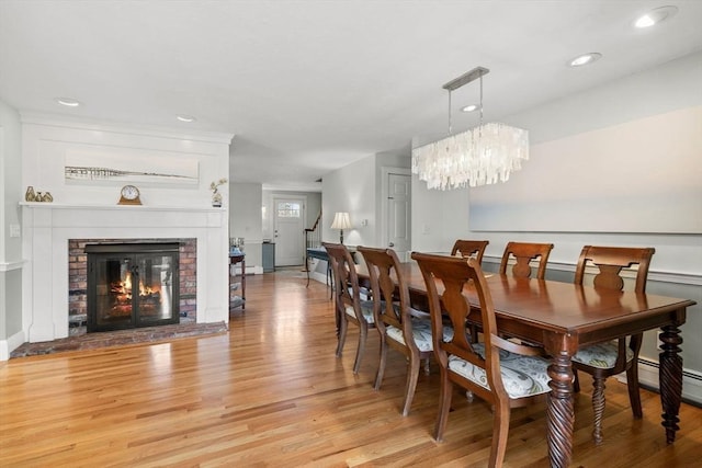 dining area with a fireplace, an inviting chandelier, recessed lighting, and light wood-style floors