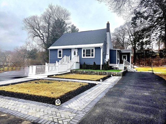 view of front of house featuring a chimney and a shingled roof