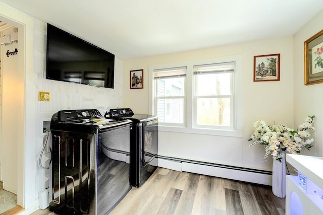 washroom featuring a baseboard heating unit, laundry area, washing machine and dryer, and light wood-style floors