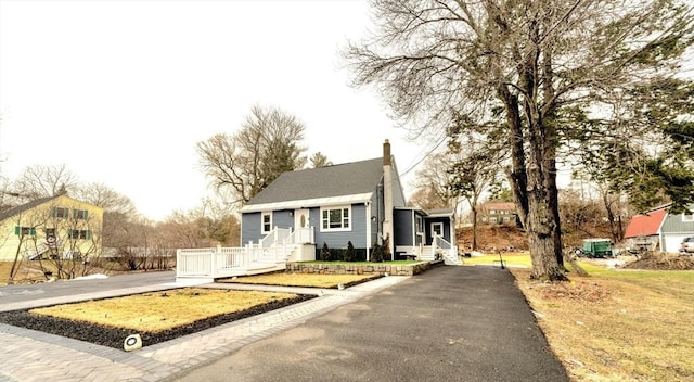 bungalow-style house featuring aphalt driveway, a chimney, and entry steps