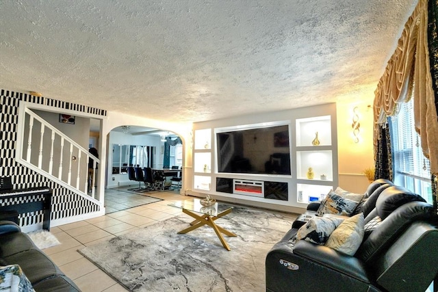 tiled living area with arched walkways, a textured ceiling, and built in shelves