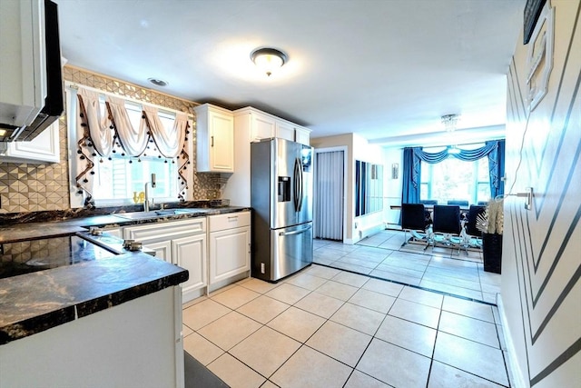 kitchen with a sink, dark countertops, stainless steel refrigerator with ice dispenser, and light tile patterned floors