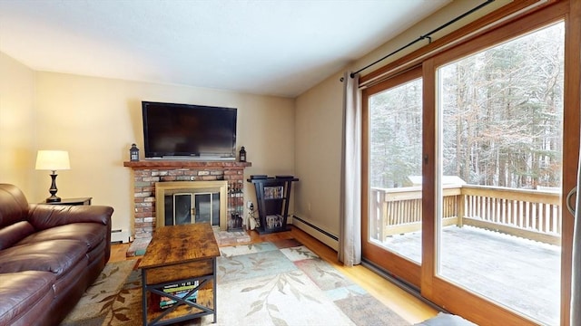 living room featuring a fireplace, a baseboard heating unit, and light wood-type flooring