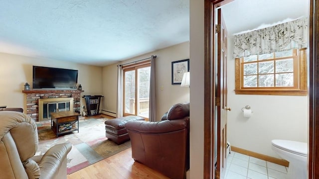 living room with a baseboard radiator, light wood-type flooring, and a brick fireplace