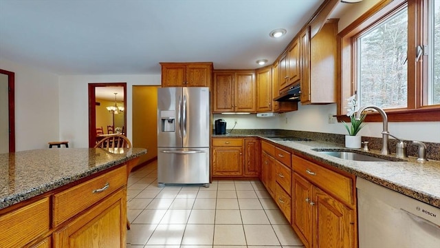 kitchen with sink, dishwasher, stainless steel fridge, and light stone countertops