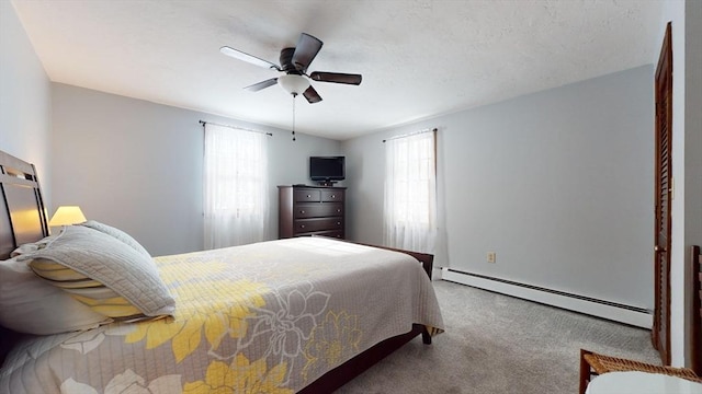 bedroom featuring a baseboard radiator, multiple windows, carpet, and ceiling fan