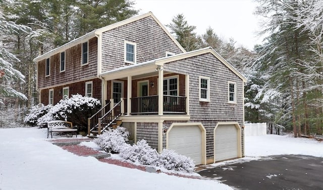 snow covered property featuring a garage and a porch