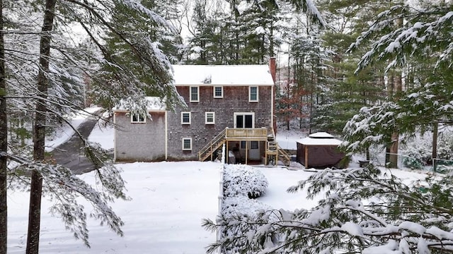 snow covered back of property featuring a wooden deck