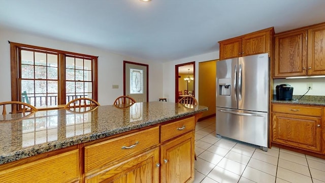 kitchen with dark stone countertops, stainless steel refrigerator with ice dispenser, and light tile patterned flooring