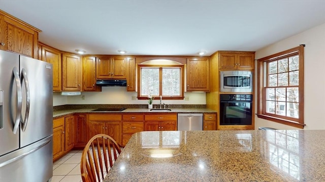 kitchen featuring sink, light tile patterned flooring, black appliances, and stone counters