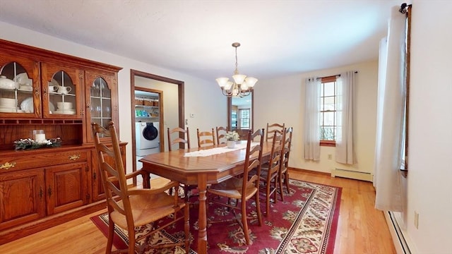 dining space featuring light wood-type flooring, a baseboard heating unit, washer / clothes dryer, and an inviting chandelier