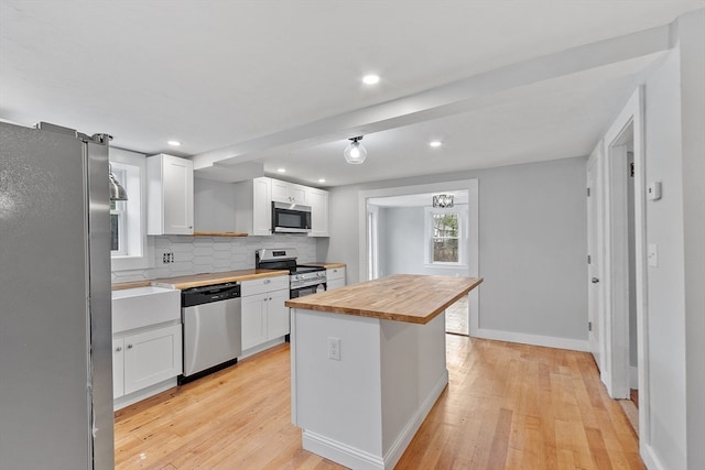 kitchen featuring white cabinetry, a center island, light hardwood / wood-style flooring, wooden counters, and appliances with stainless steel finishes