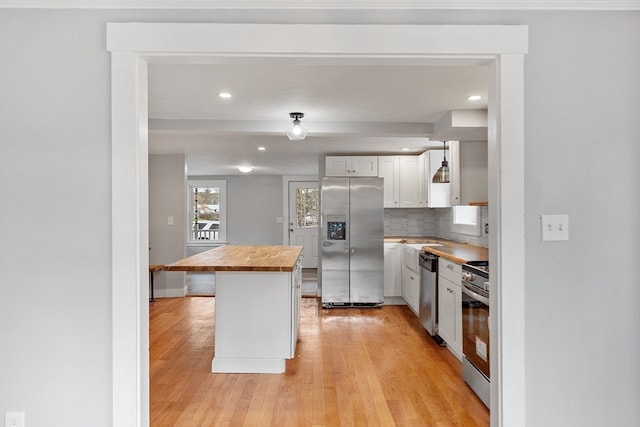 kitchen featuring white cabinetry, light hardwood / wood-style floors, appliances with stainless steel finishes, and butcher block counters