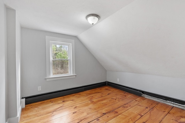 additional living space with light hardwood / wood-style flooring and lofted ceiling