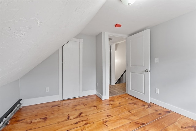 additional living space with light hardwood / wood-style flooring and vaulted ceiling