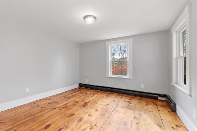 spare room featuring baseboard heating and light hardwood / wood-style floors