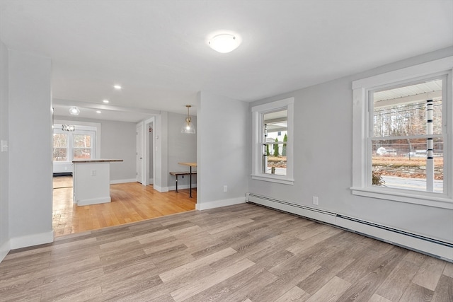 unfurnished living room featuring light wood-type flooring, a notable chandelier, and a baseboard heating unit