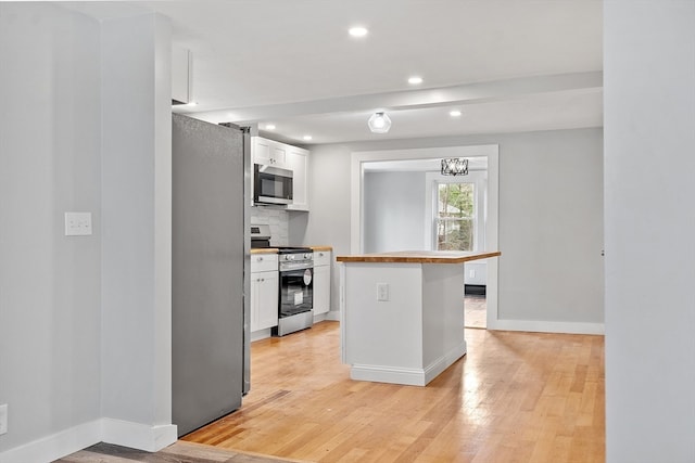 kitchen featuring decorative backsplash, stainless steel appliances, a notable chandelier, white cabinets, and light hardwood / wood-style floors