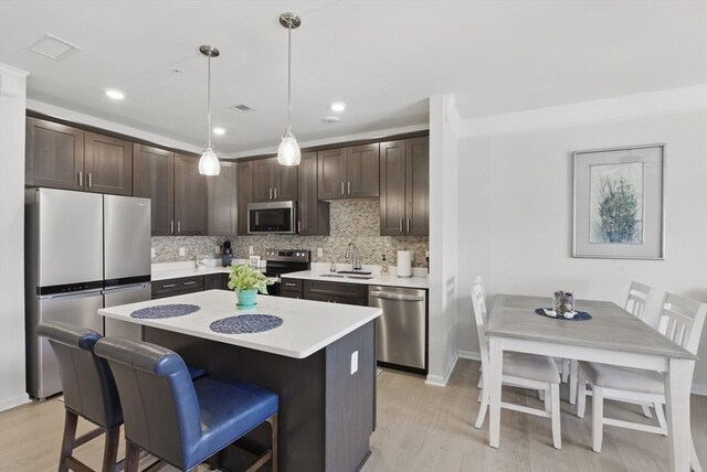 kitchen with dark brown cabinetry, light wood-type flooring, a sink, light countertops, and stainless steel appliances