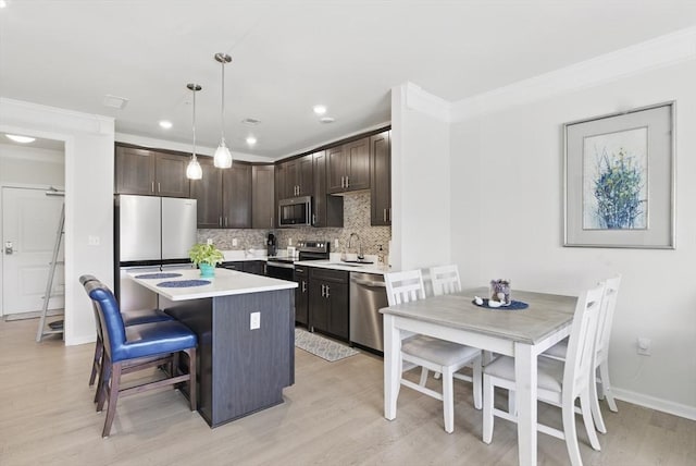 kitchen featuring dark brown cabinets, a center island, light wood-style flooring, backsplash, and stainless steel appliances