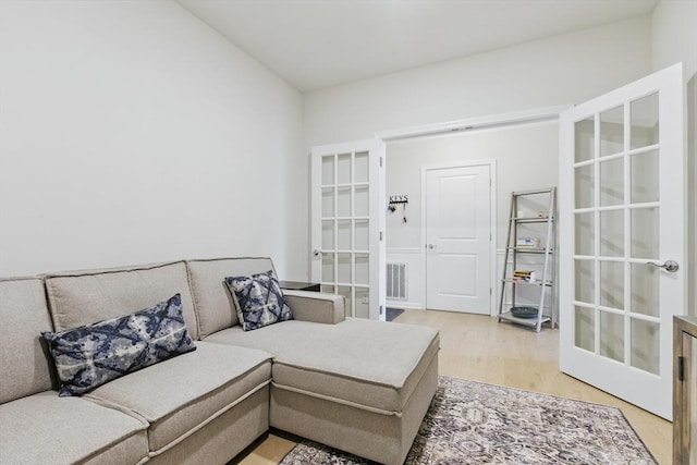 living area featuring french doors, light wood-style flooring, and visible vents
