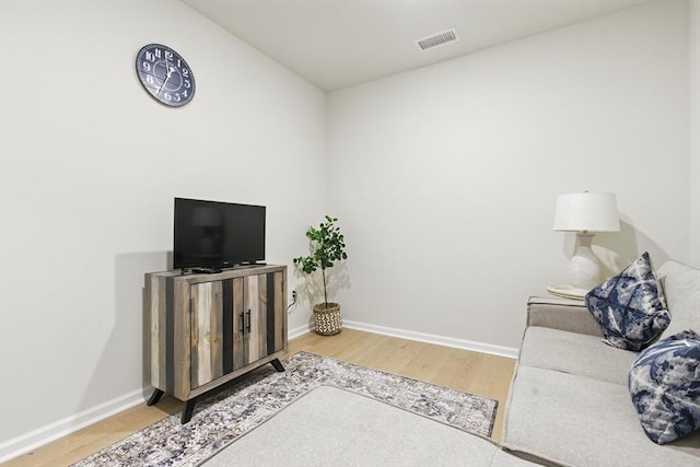 living room featuring baseboards, wood finished floors, and visible vents