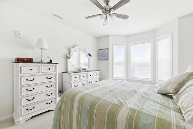 bedroom with light colored carpet, a ceiling fan, visible vents, and multiple windows