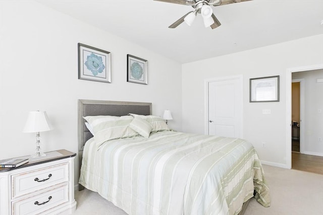 bedroom featuring light colored carpet, a ceiling fan, and baseboards
