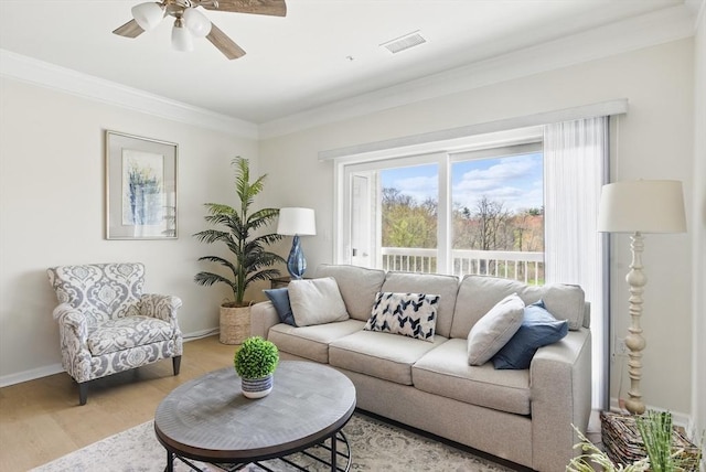 living room with a ceiling fan, baseboards, light wood-type flooring, visible vents, and ornamental molding