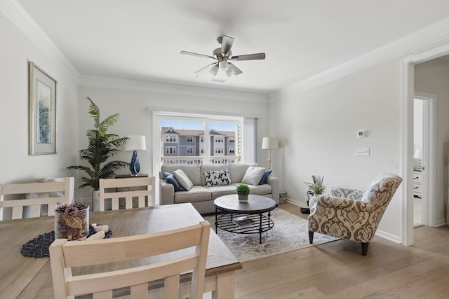living room with crown molding, ceiling fan, baseboards, and light wood finished floors