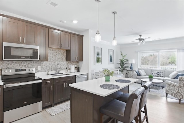 kitchen with a sink, light countertops, light wood-style floors, and stainless steel appliances