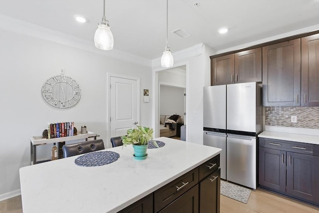 kitchen with freestanding refrigerator, dark brown cabinets, light countertops, backsplash, and hanging light fixtures