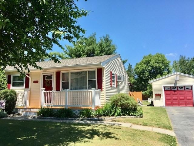 view of front of house featuring covered porch, a front yard, an outdoor structure, and a garage