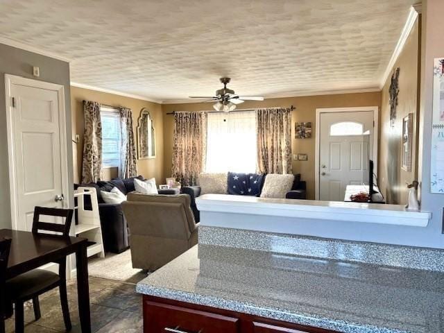 living room featuring ceiling fan, a textured ceiling, and ornamental molding