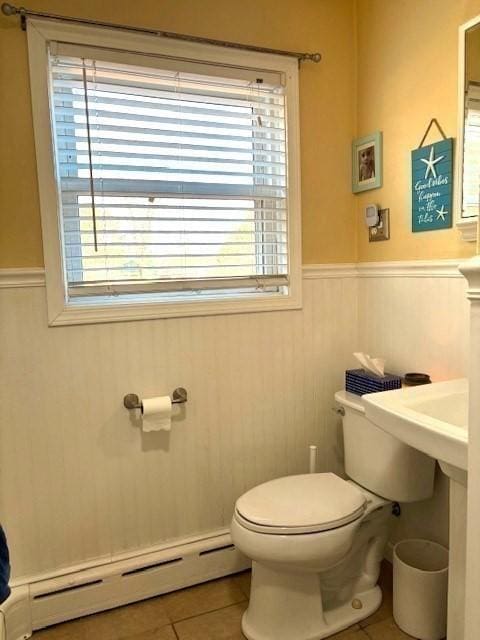 bathroom with toilet, baseboard heating, and tile patterned flooring