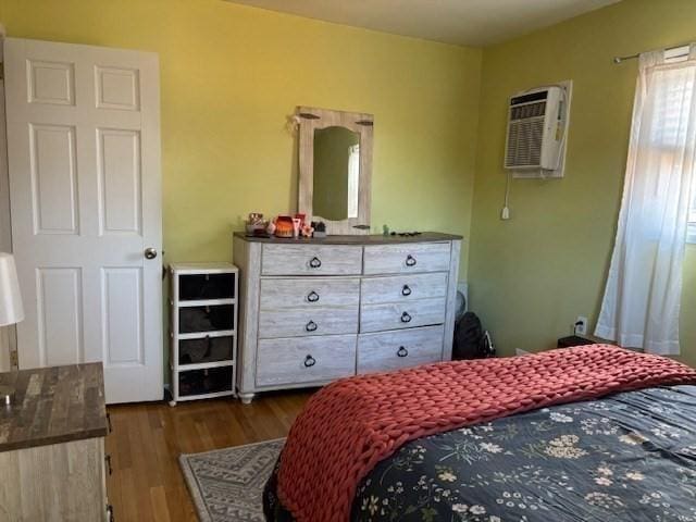 bedroom with a wall mounted air conditioner and dark hardwood / wood-style flooring