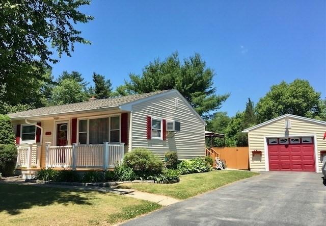 view of front of home featuring a garage, covered porch, an outbuilding, and a front yard