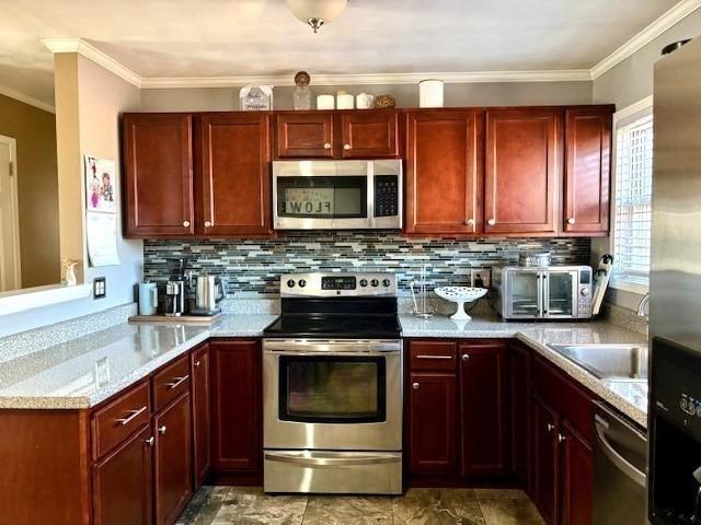 kitchen with crown molding, tasteful backsplash, light stone countertops, and appliances with stainless steel finishes