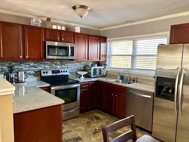 kitchen featuring sink, ornamental molding, appliances with stainless steel finishes, and tasteful backsplash