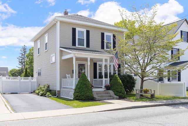 american foursquare style home with a porch, a chimney, and fence
