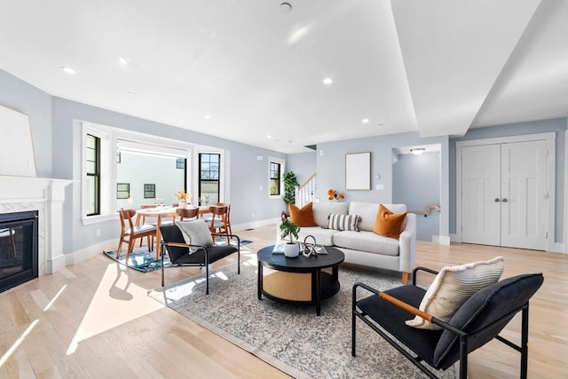 living area featuring light wood-type flooring, a fireplace, baseboards, and recessed lighting