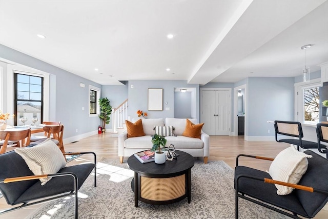 living area with light wood-style flooring, recessed lighting, stairway, and baseboards