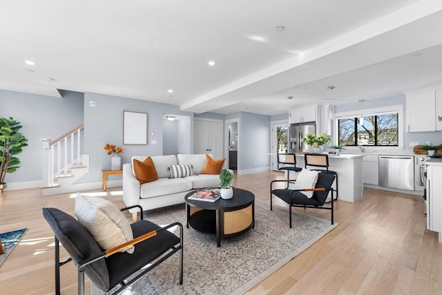 living area featuring light wood-style floors, stairs, baseboards, and recessed lighting