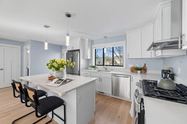 kitchen featuring appliances with stainless steel finishes, light countertops, a breakfast bar area, and white cabinetry